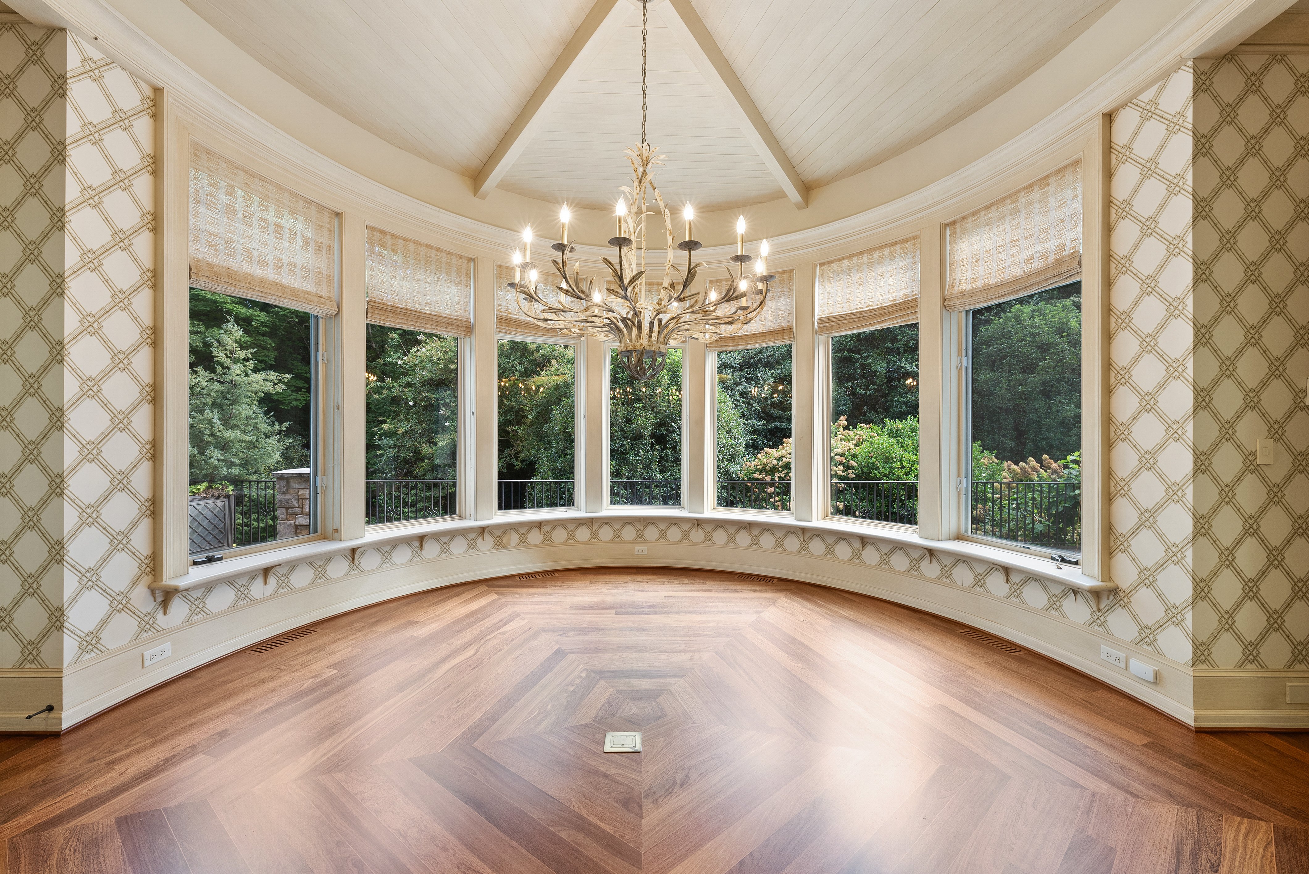 A round room with bay windows and a chandelier
