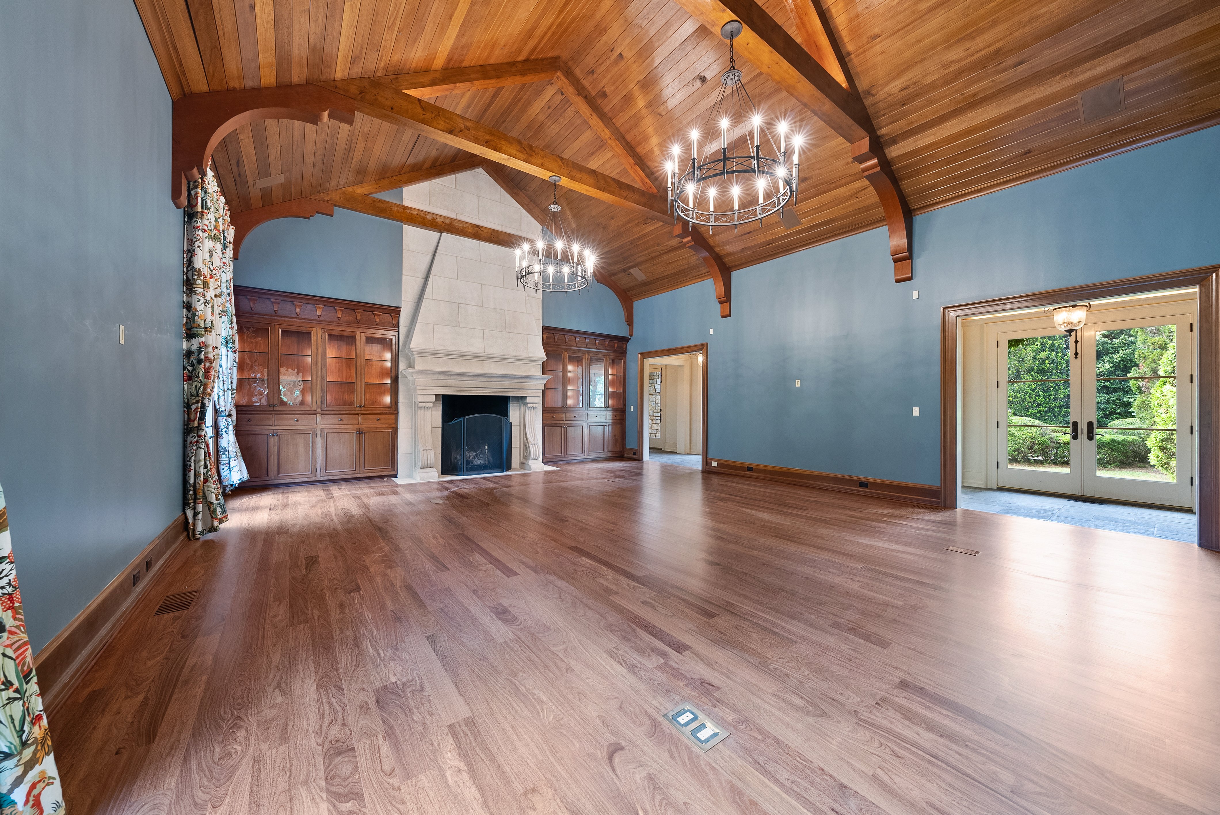 Grand room with blue walls, vaulted ceiling, and hardwood floors