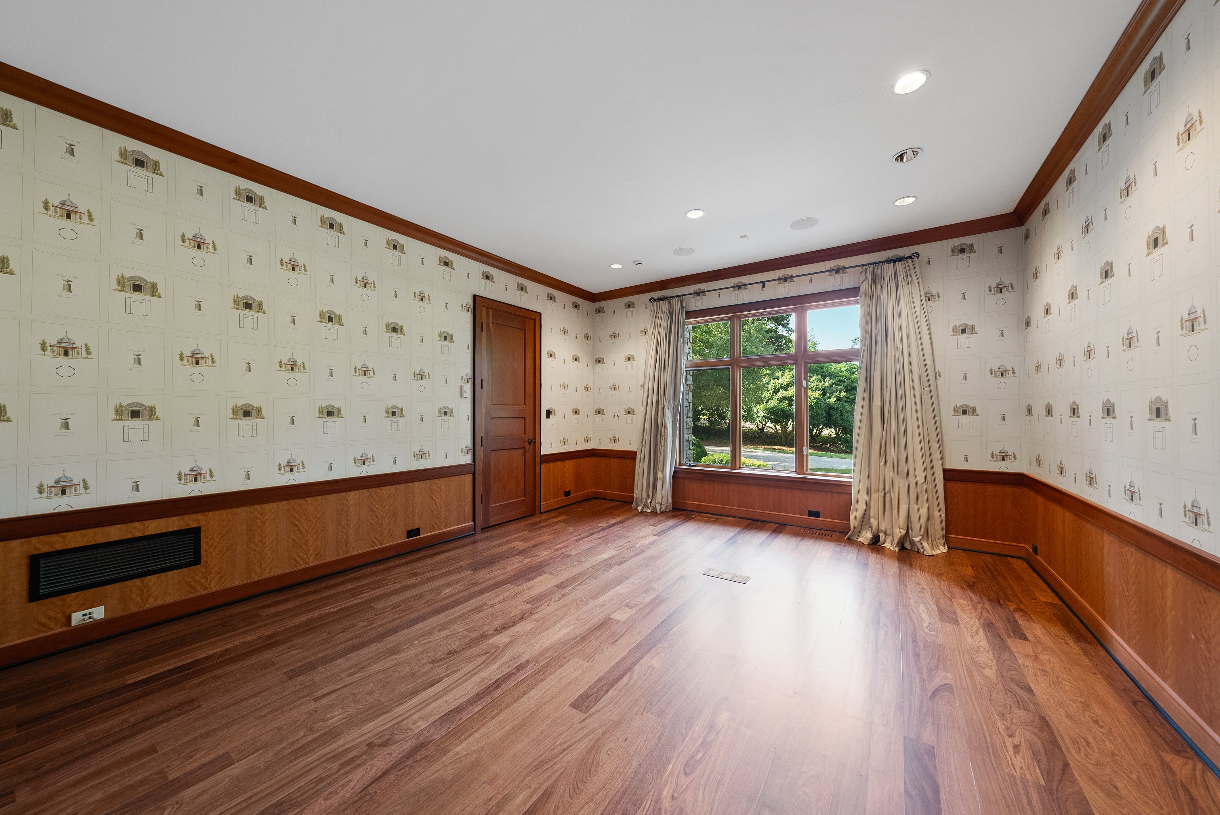 Bedroom or spare room with hardwood floors, wallpaper, and a large window with curtains