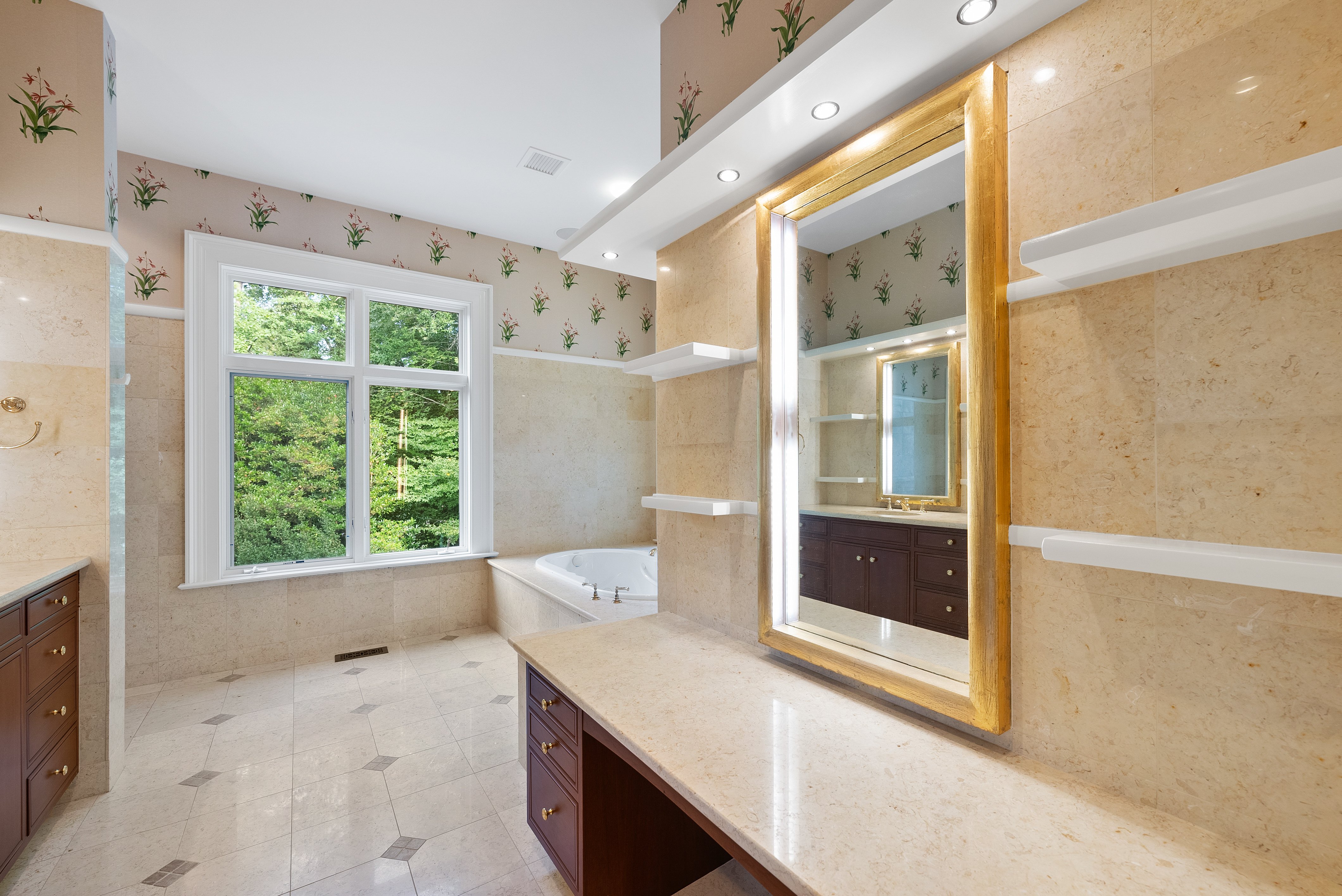 Interior of a bathroom with a mirror in the foreground and a large tub in the background.