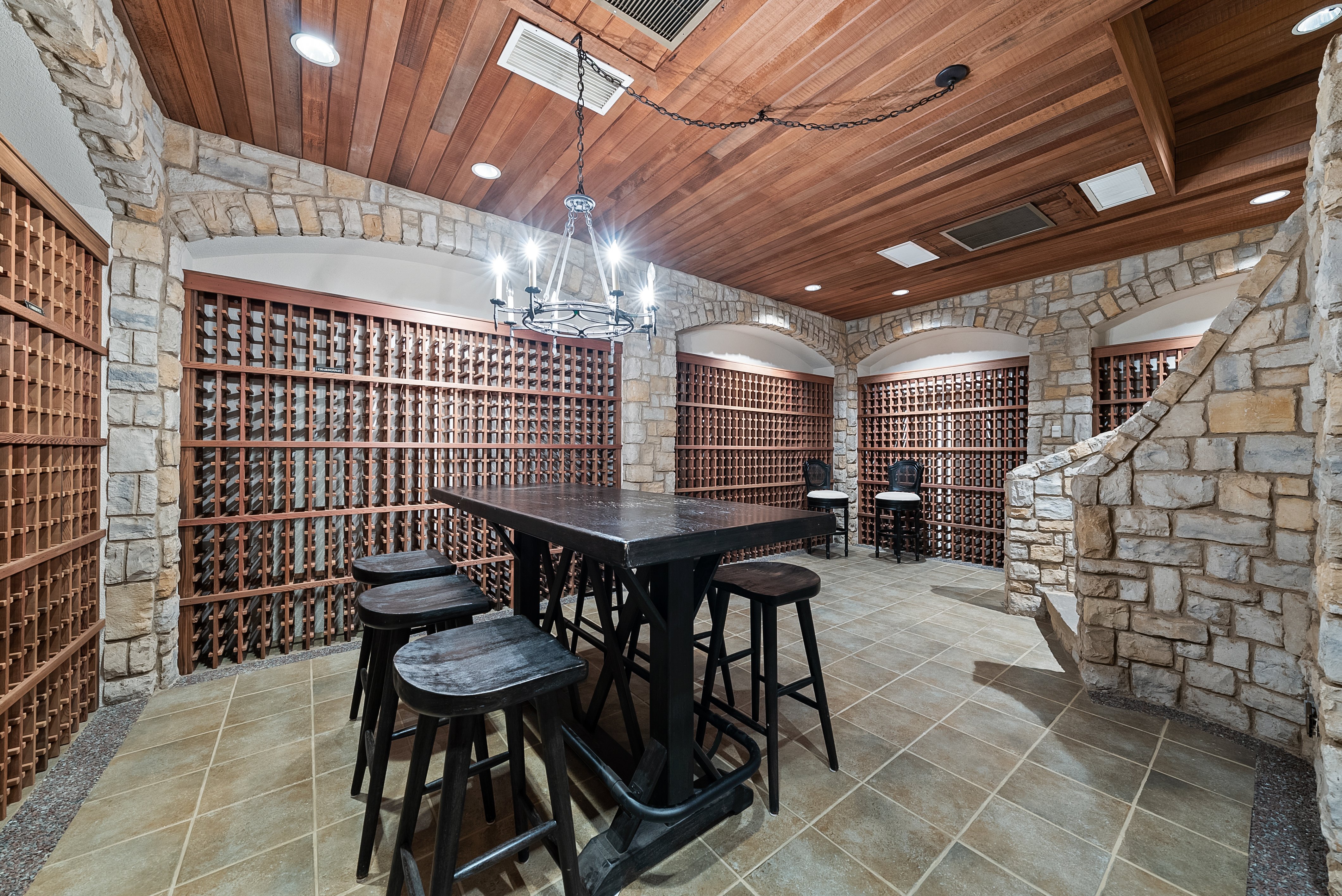 An alternate view of the wine celler, with a larger focus on the bartop and stools, wine racks on the wall.