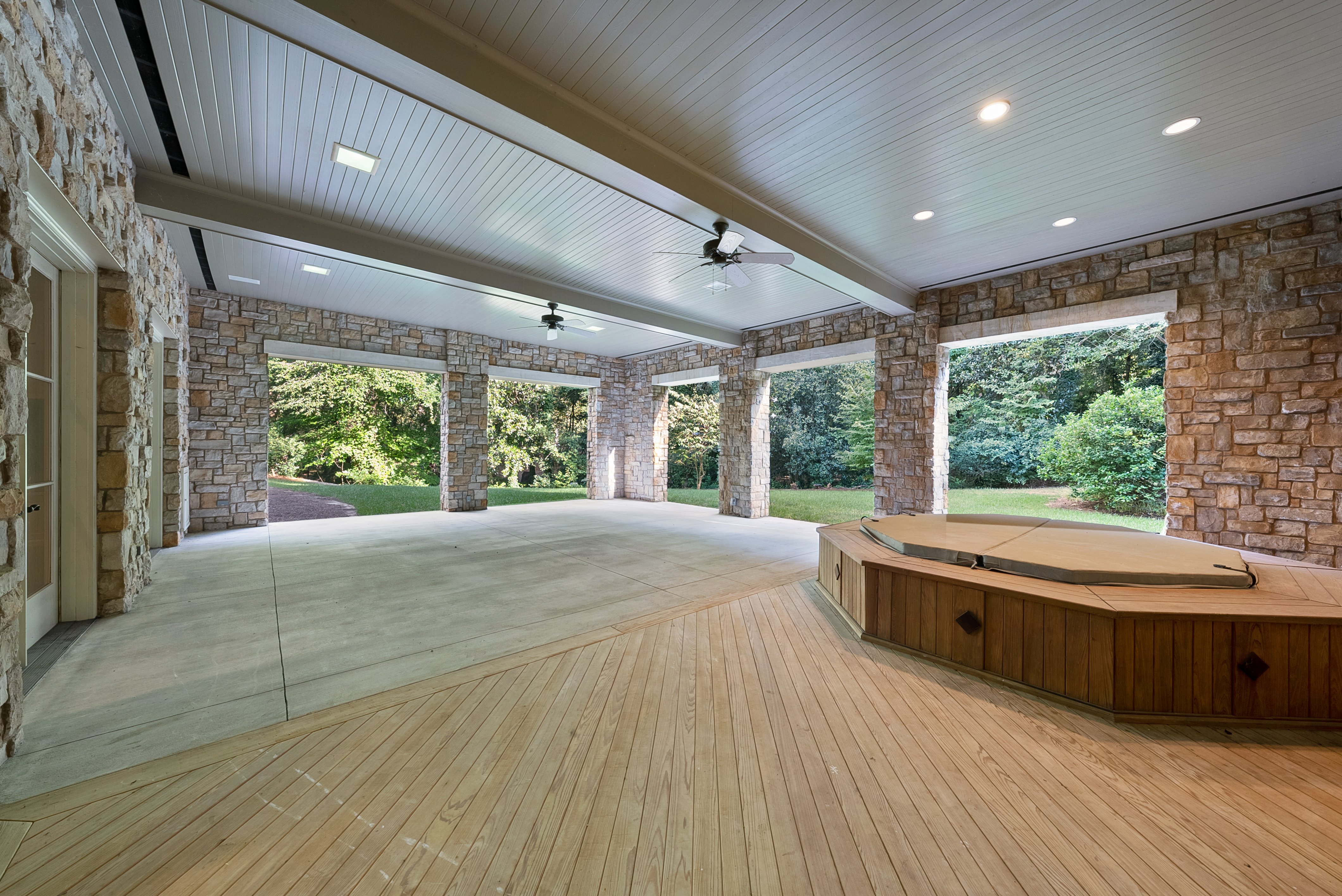 An exterior view of a paved patio, hot tub or jacuzzi in the corner.
