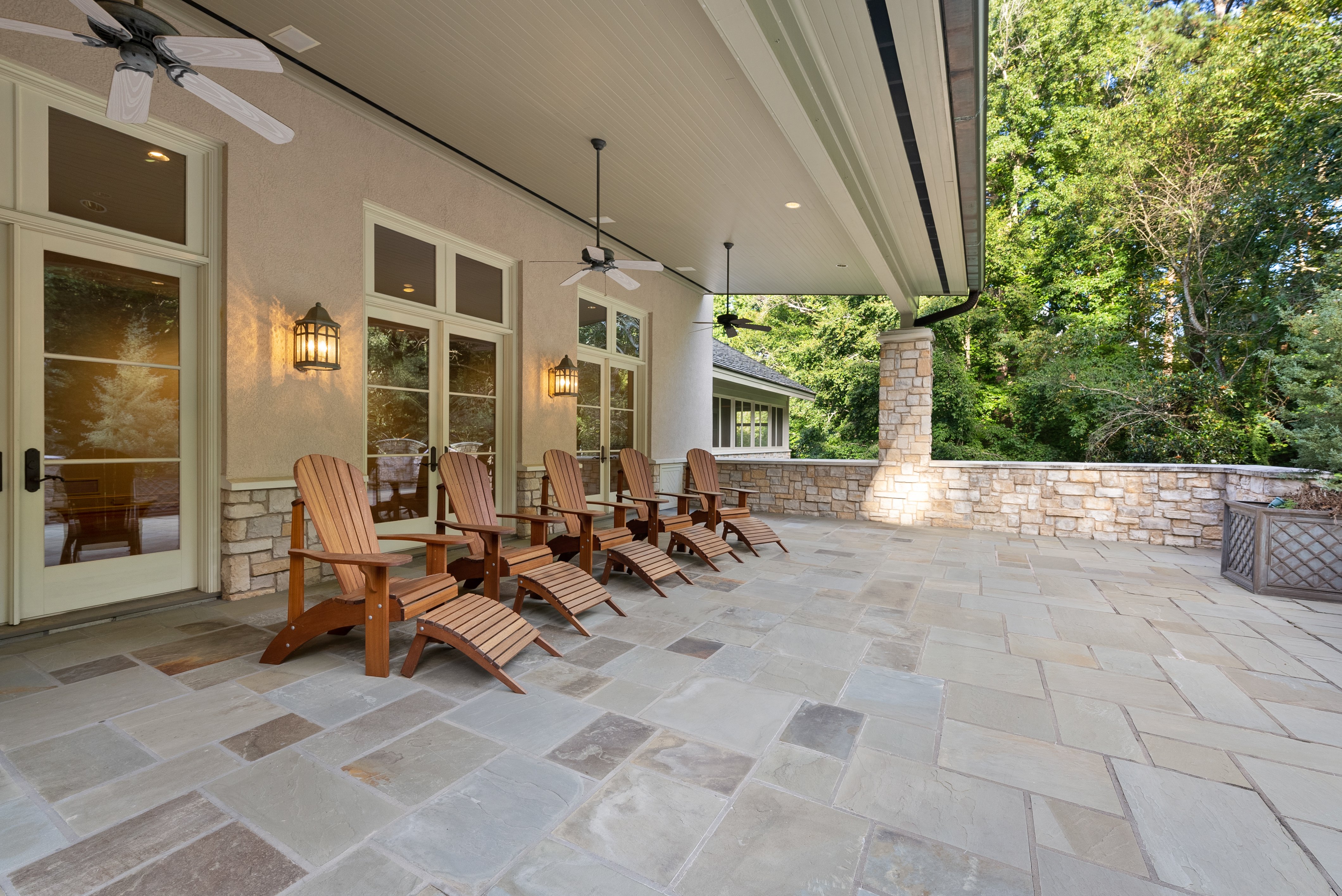 An alternate view of the tiled patio with five wooden reclining chairs.