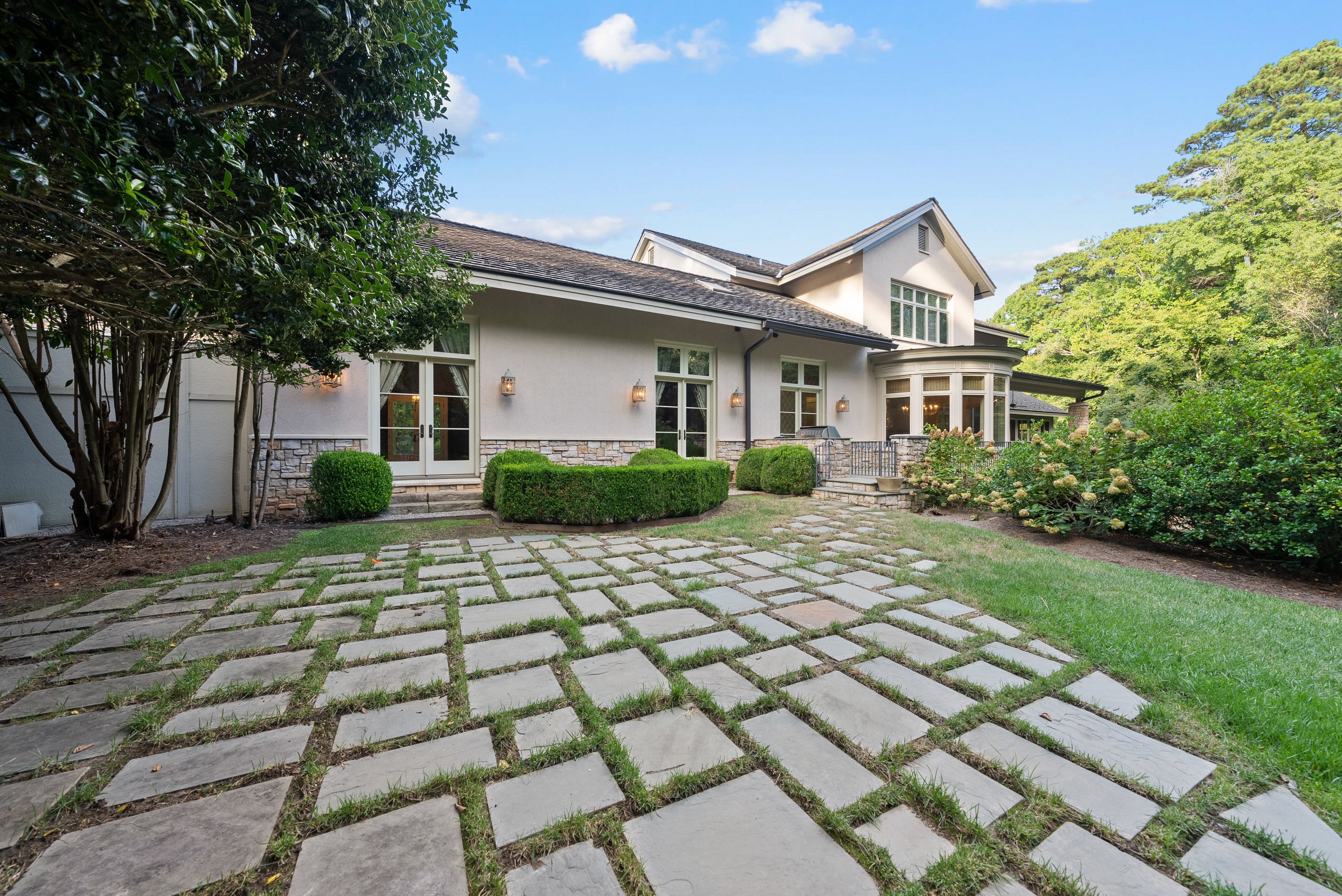 An exterior view of the home, showing a stone-tiled walkway with grass sprouting between the stones for a natural look